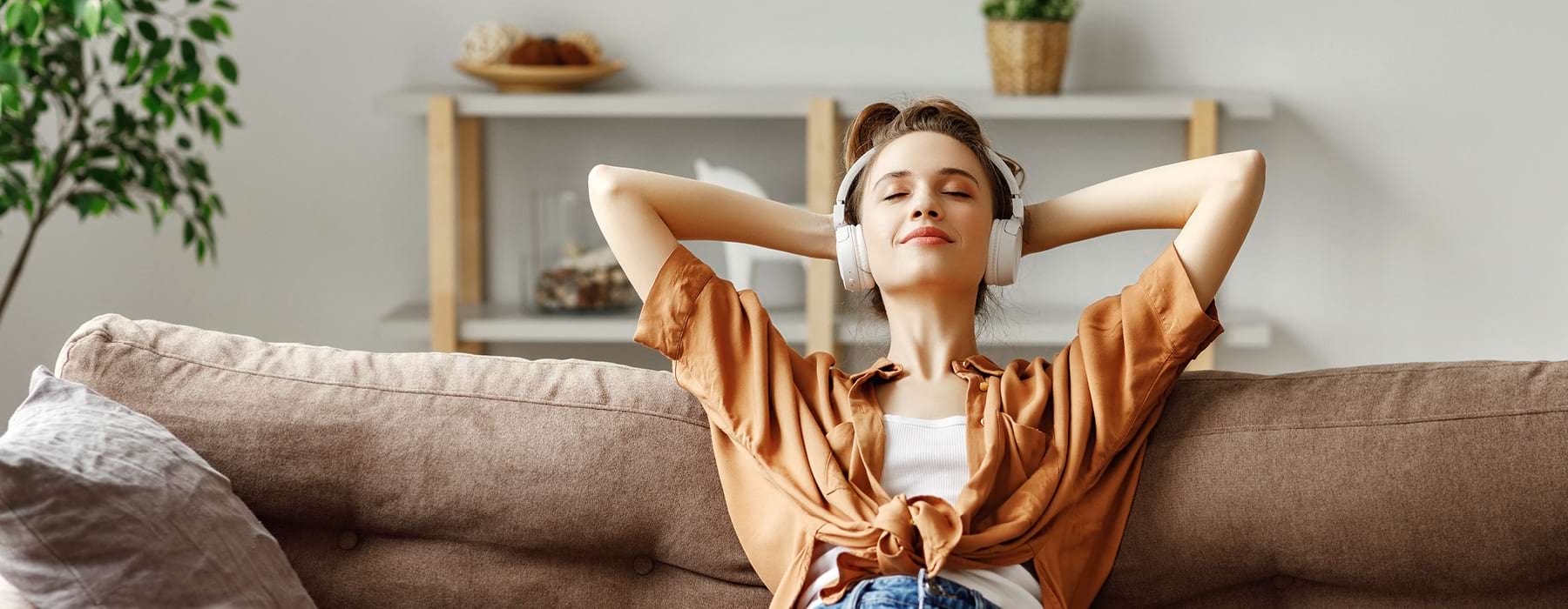 resident with headphones, relaxes on her couch